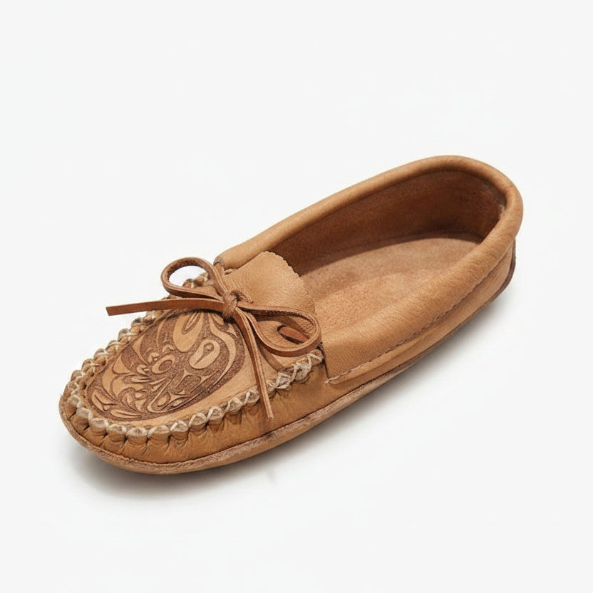 A single tan leather moccasin slipper with hand-tooled floral detailing on the toe and a matching leather tie, shown on a clean white background.
